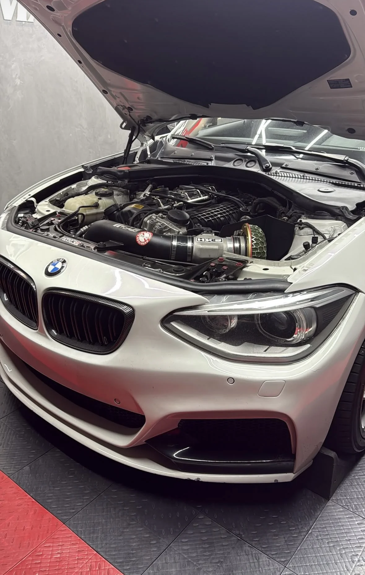 Vão do motor do BMW Série 1 com admissão esportiva instalada — tubulação preta e filtro cônico