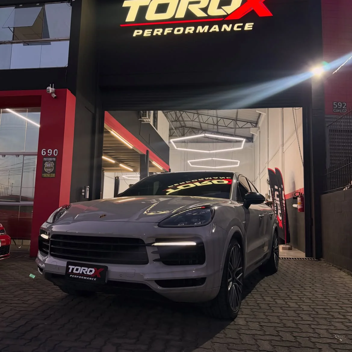 Porsche Cayenne Coupé cinza de três quartos dianteiro sob o letreiro da fachada da TORQX